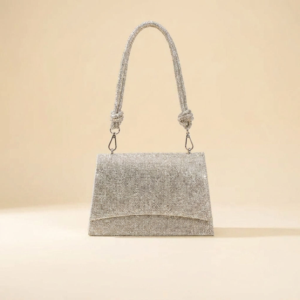Petit sac à main à rabat pavé de cristaux argentés, porté par une ganse en cordelette nouée avec mousquetons.