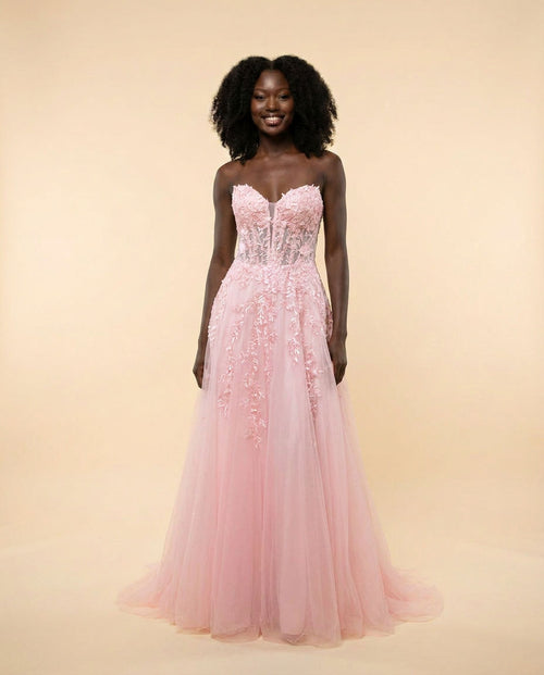 Robe de bal sans bretelles à bustier corset et appliqués floraux, jupe de tulle évasée, présentée sur mannequin en boutique.