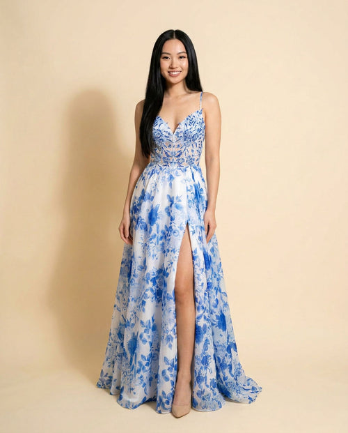 Robe de bal évasée à imprimé floral bleu sur fond blanc, bretelles fines, décolleté en V, bustier brodé et fente haute.