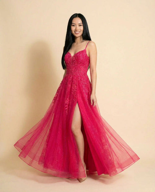 Robe de bal magenta à bretelles fines, bustier de dentelle appliquée et jupe de tulle évasée avec fente haute au devant.