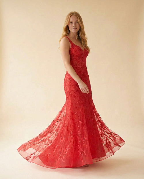 Femme portant une robe de bal sirène rouge en dentelle appliquée, décolleté en cœur et longue traîne de tulle brodée.