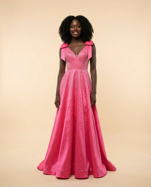 Femme portant une robe de bal rose flamboyant à boucles aux épaules, décolleté en V, bustier scintillant et jupe ample avec traîne.