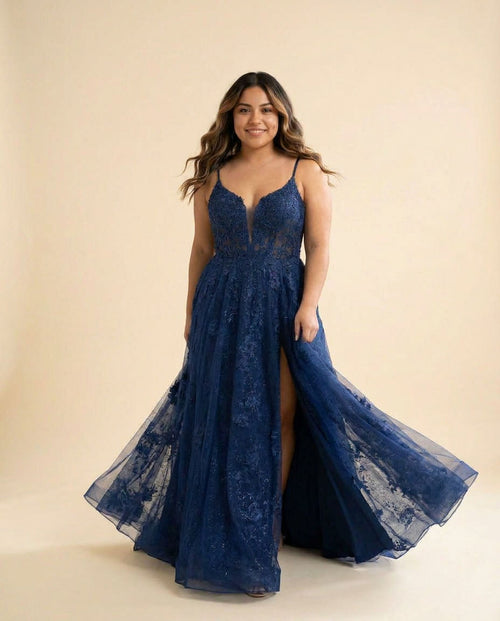 Femme portant une robe de bal évasée bleu marine à bustier de dentelle semi-transparent, décolleté cœur et jupe de tulle scintillant avec fente haute.