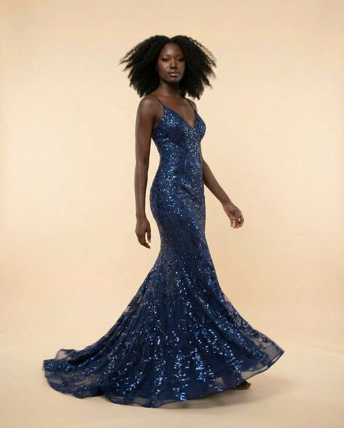 Femme portant une robe sirène bleu marine à paillettes florales, décolleté en V et fines bretelles, avec longue traîne.