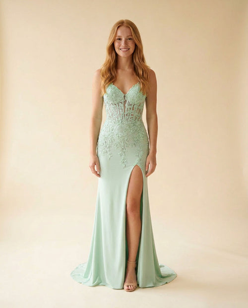 Femme portant une robe de bal vert menthe à bustier corset transparent brodé de dentelle florale, jupe sirène en satin avec fente haute, vue de face.