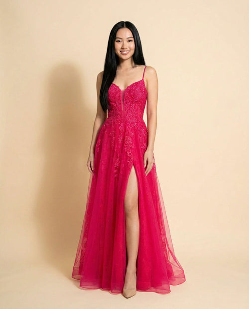 Robe de bal magenta à bretelles fines, bustier de dentelle appliquée et jupe de tulle évasée avec fente haute au devant.