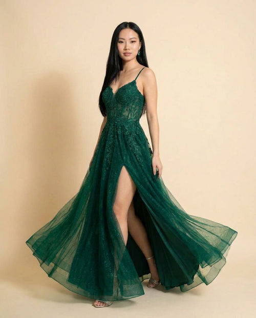 Robe de bal évasée vert émeraude à bustier corseté en dentelle, décolleté en cœur, fines bretelles et jupe de tulle avec fente haute, vue de devant.