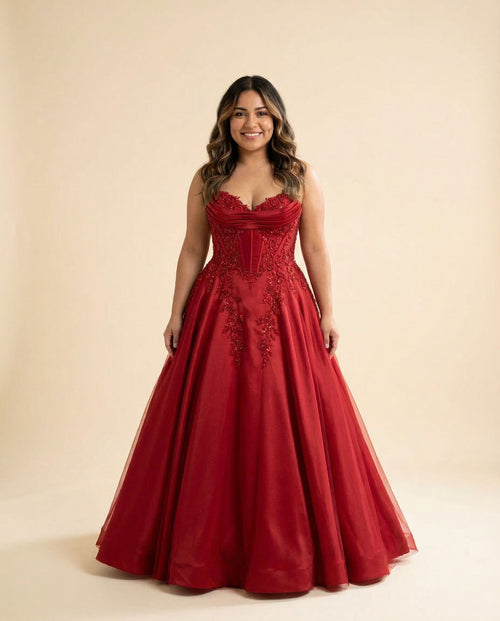 Femme portant une robe de bal rouge à bustier décolleté cœur, dentelle perlée et jupe de satin ample, vue de face.