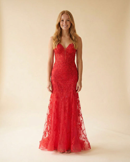 Femme portant une robe de bal sirène rouge en dentelle appliquée, décolleté en cœur et longue traîne de tulle brodée.