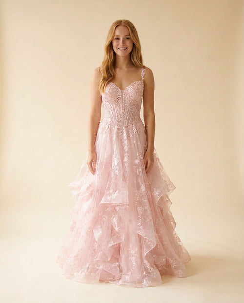 Robe de bal rose pâle en dentelle florale, bustier à décolleté cœur et jupe évasée à étages de tulle, sur mannequin en boutique.