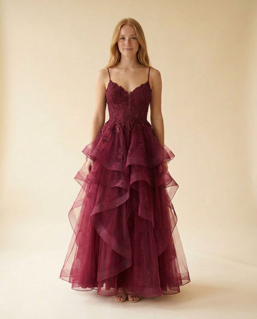Robe de bal bourgogne à bustier de dentelle florale, décolleté cœur et fines bretelles, avec ample jupe de tulle à étages froncés, vue de face.