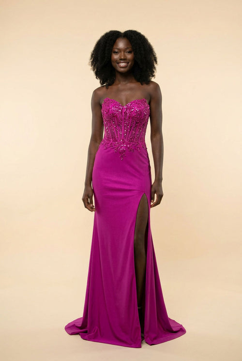 Femme portant une robe de bal magenta à bustier corset pailleté, décolleté cœur et fente haute, debout devant un escalier de marbre.