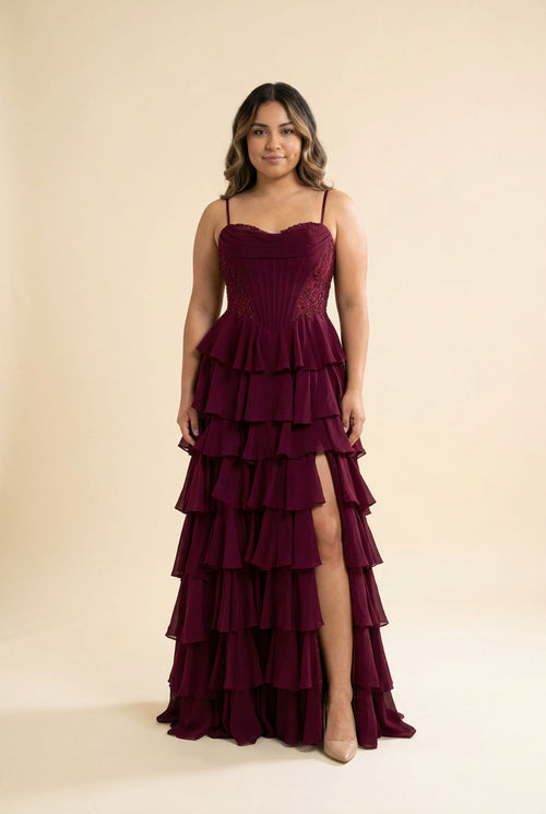 Robe de bal bourgogne à bretelles fines, bustier structuré et jupe de mousseline à volants étagés avec fente haute, vue de face.