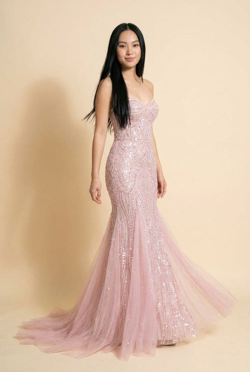 Femme portant une robe sirène rose pâle au bustier perlé sans bretelles et à jupe de tulle scintillant.