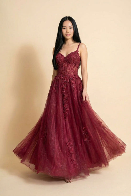 Robe de bal à corset de dentelle florale avec décolleté en cœur et jupe de tulle scintillant, présentée devant des falaises rouges.