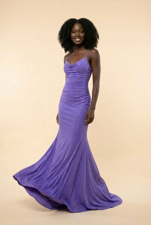 Robe de bal sirène violet à décolleté cœur et fines bretelles, tissu chatoyant avec traîne, portée devant des parois rocheuses.