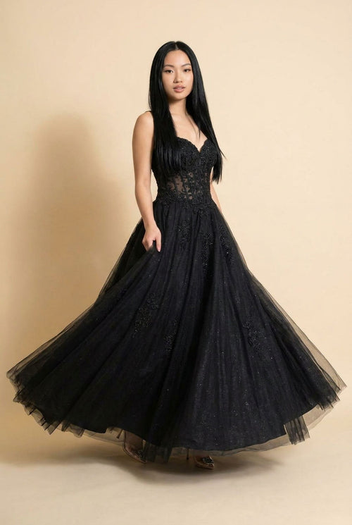 Femme portant une robe de bal noire à bustier de dentelle ajourée, décolleté cœur et jupe de tulle volumineuse.