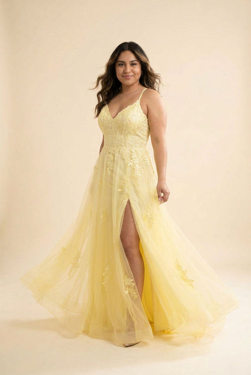 Femme portant une robe évasée en tulle à bustier de dentelle, décolleté en cœur, bretelles fines et fente haute, devant la mer.