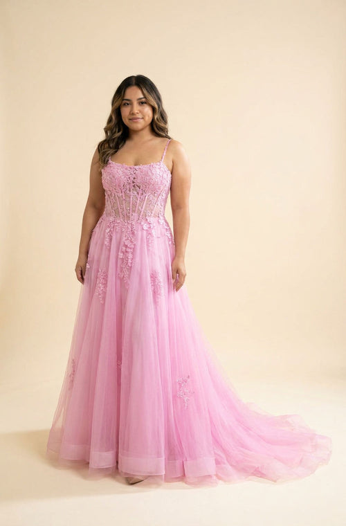 Femme portant une robe de bal rose bonbon à corset baleiné, dentelle florale et jupe ample en tulle, vue de face.