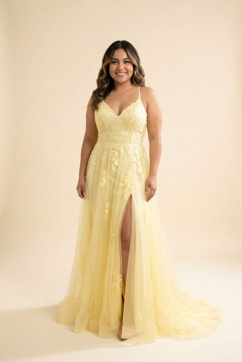Femme portant une robe évasée en tulle à bustier de dentelle, décolleté en cœur, bretelles fines et fente haute, devant la mer.