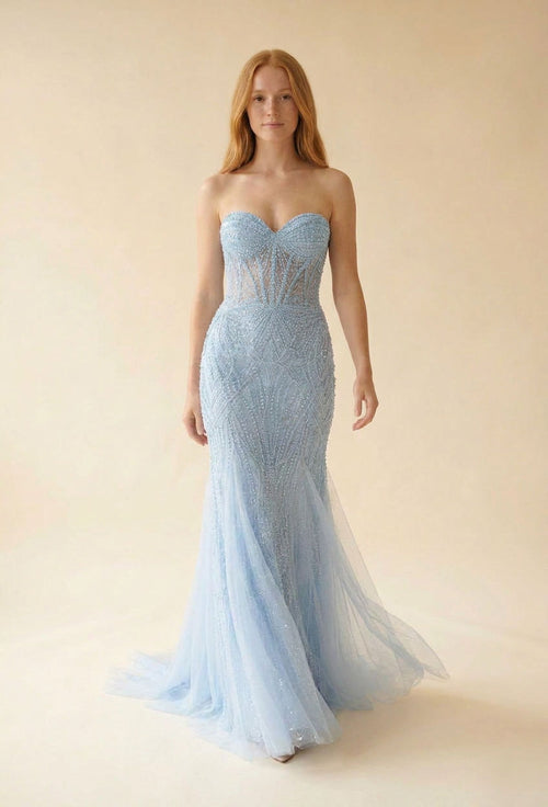 Femme portant une robe de bal sirène bleu pâle à bustier perlé transparent et décolleté en cœur, jupe de tulle scintillant.