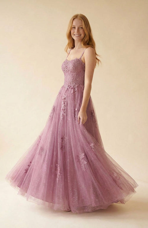 Femme portant une robe de bal princesse violet aubergine à bustier de dentelle et jupe de tulle scintillante, debout sur une terrasse.