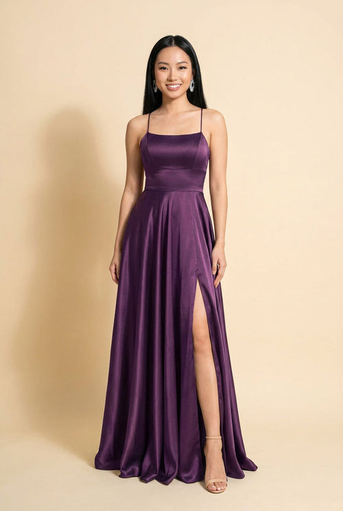 Femme portant une robe de bal en satin prune à encolure droite, bretelles fines, jupe évasée avec fente haute et traîne.