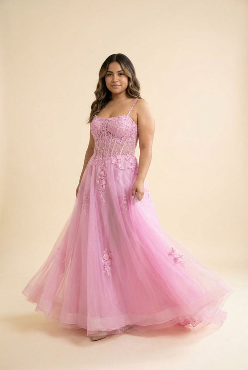 Femme portant une robe de bal rose bonbon à corset baleiné, dentelle florale et jupe ample en tulle, vue de face.