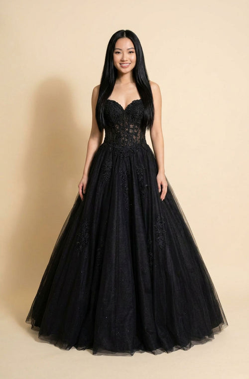 Femme portant une robe de bal noire à bustier de dentelle ajourée, décolleté cœur et jupe de tulle volumineuse.