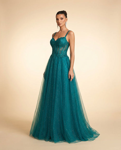 Femme portant une robe de bal vert émeraude à bustier en dentelle florale, décolleté cœur et jupe de tulle scintillant évasée.