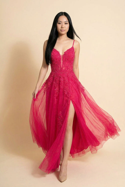 Femme portant une robe de bal rose bonbon à corsage de dentelle brodée, décolleté cœur et jupe de tulle évasée avec fente à l'avant.