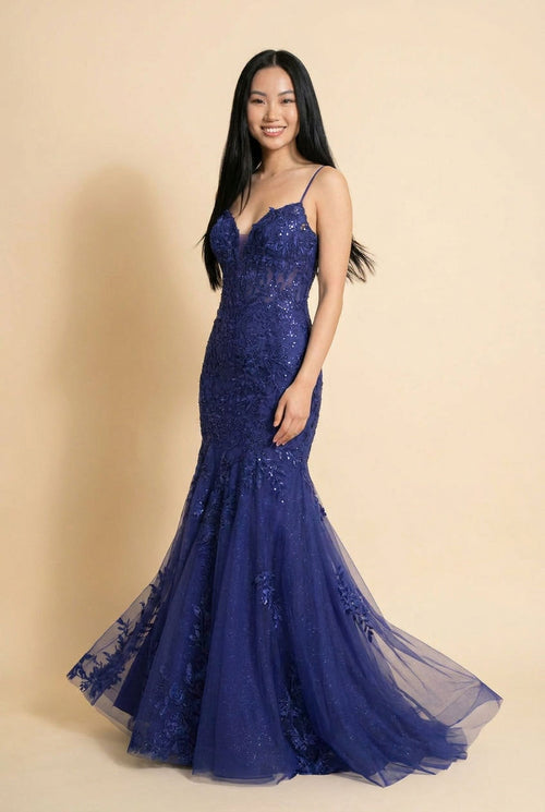 Femme portant une robe sirène indigo à bustier de dentelle florale, décolleté plongeant et jupe de tulle évasée scintillante.