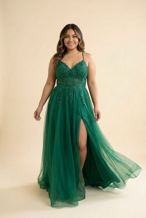 Femme portant une robe de bal évasée en tulle et dentelle à décolleté en cœur et fente haute, devant un décor méditerranéen ensoleillé.