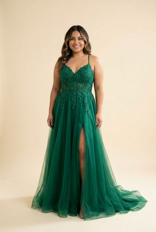 Femme portant une robe de bal évasée en tulle et dentelle à décolleté en cœur et fente haute, devant un décor méditerranéen ensoleillé.